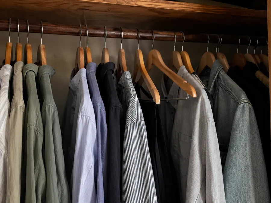 Blick in einen offenen Kleiderschrank mit Holzkleiderbügeln, die überwiegend in eine Richtung zeigen, zwei bis drei sind umgedreht