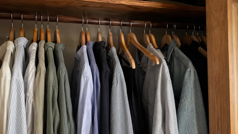 Blick in einen offenen Kleiderschrank mit Holzkleiderbügeln, die überwiegend in eine Richtung zeigen, zwei bis drei sind umgedreht