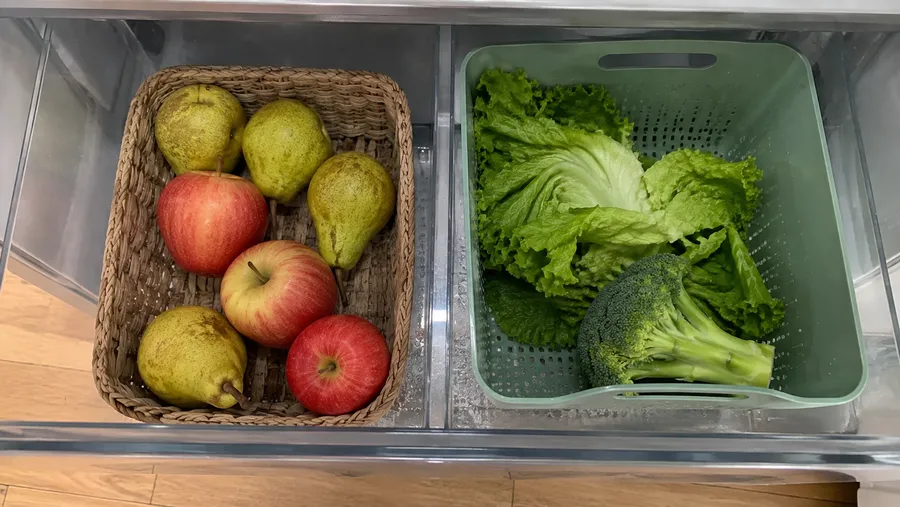 Blick von oben ins Gemüsefach, Äpfel im Körbchen getrennt von Blattsalat in belüfteter Box