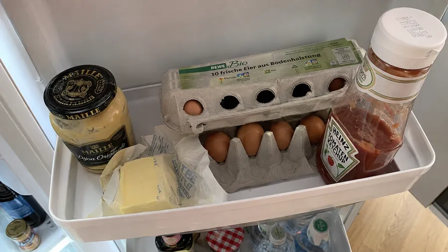 Nahaufnahme der Kühlschranktür-Fächer mit Senfglas, Butter, Eierfach und Ketchup