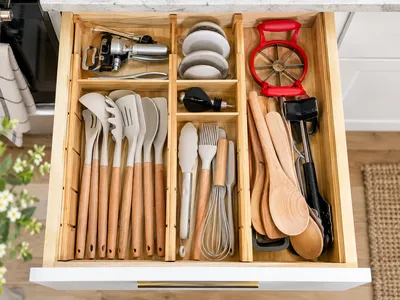 Draufsicht auf eine perfekt organisierte Küchenschublade mit Kochlöffeln, Schneebesen und Küchenhelfern in klar getrennten Fächern